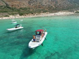 A lively scene featuring a group enjoying a day on the water with multiple boats anchored in stunning turquoise waters, perfect for swimming and beach activities.