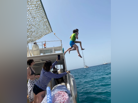 Two children joyfully leap off the side of a boat into the sparkling blue water, capturing the essence of summer fun and adventure on the water.