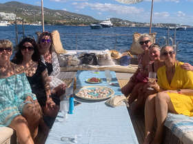 A joyful group of friends enjoys a sunny day on a yacht, celebrating with cocktails and delicious food — perfect for a memorable getaway on the water.