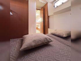 A cozy cabin interior featuring comfortable pillows and a view into the boat's living area, perfect for relaxing during a sailing trip.