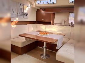 A cozy interior view of a boat's dining area featuring a table set with a plate of pastries, perfect for enjoying meals while cruising.