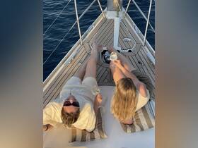 Two friends enjoy cocktails on the deck of a yacht, soaking up the sun and making memories — a perfect setting for relaxation and celebration on the water.