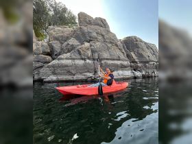 A man enjoys kayaking near impressive rock formations, showcasing the thrill of water activities and outdoor adventures.