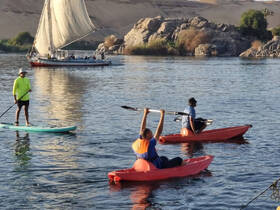 A vibrant scene of people kayaking and paddleboarding on tranquil waters, with a traditional sailboat in the background, showcasing the joy of on-water adventures.