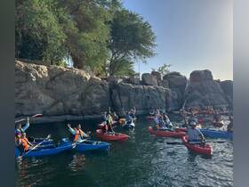 A lively group of kayakers enjoys a day on the water, celebrating their adventure amidst stunning rock formations — perfect for outdoor enthusiasts.