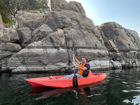 A kayaker enjoys paddling near stunning rock formations, showcasing the beauty of outdoor water adventures.