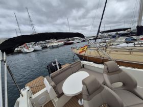 Interior view of a boat's seating area, showcasing comfortable chairs and a table, perfect for relaxing while docked.