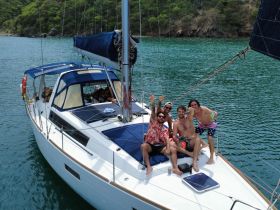 A lively group of friends celebrates aboard a sailboat, enjoying the sun and water — perfect for memorable sailing adventures.