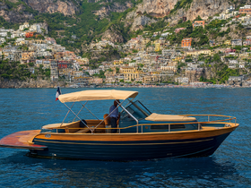 A stylish boat navigates the stunning Amalfi Coast, showcasing its elegant design against a backdrop of colorful hillside villages.