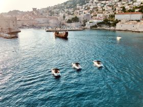 A picturesque view of boats navigating through a scenic harbor, with a charming cityscape in the background — perfect for capturing the essence of coastal adventures.