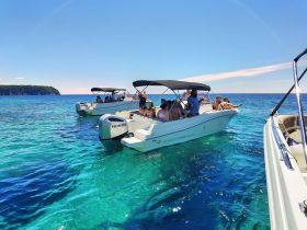 A lively group enjoys a day on the water aboard multiple boats, surrounded by stunning clear blue waters — perfect for a fun-filled boating adventure.