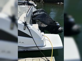 Close-up view of a sleek boat's exterior featuring outboard motors, docked at a marina. Ideal for showcasing vessel details and design.