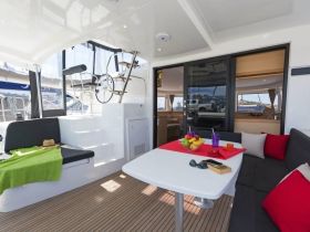 A stylish interior view of a boat's cabin featuring comfortable seating and a dining area, perfect for relaxing and enjoying meals while on the water.
