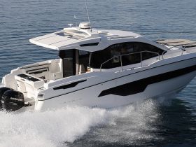 A sleek speedboat, the Karnic, glides through clear waters, showcasing its modern design and performance capabilities.