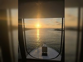 A stunning sunset view from the bow of a boat, showcasing the tranquil waters and a picturesque horizon — perfect for evening cruises.