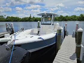 A sleek center console boat docked at a marina, showcasing its modern design against a serene water backdrop — perfect for fishing or leisure outings.