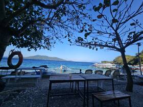A picturesque view of a beachside scene with boats anchored in the clear waters, framed by trees and a vibrant landscape — perfect for a relaxing getaway or island exploration.