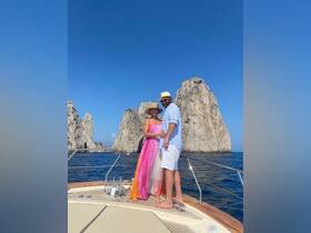 A couple enjoys a romantic moment on the bow of a boat, surrounded by stunning rock formations and clear blue waters — perfect for unforgettable memories on the water.