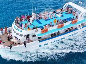 A lively group enjoys a cruise aboard the 'Blue Lagoon' boat, surrounded by stunning ocean views — perfect for social gatherings and memorable experiences on the water.