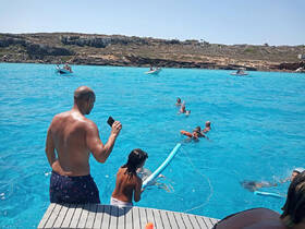 A lively scene of a family enjoying a day in the turquoise waters, with kids playing and adults capturing memories on their phones — perfect for summer adventures.