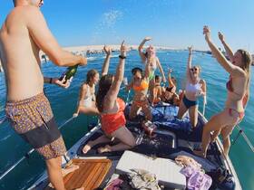 A lively group celebrates on a boat, popping champagne and enjoying the sun — perfect for unforgettable summer parties and gatherings on the water.