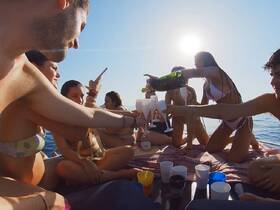A lively group celebrates on a boat, pouring cocktails and enjoying the sunshine — perfect for summer parties and memorable gatherings on the water.