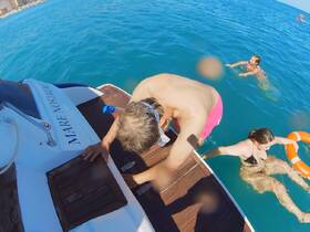 A lively scene of guests enjoying a refreshing swim from the boat 'Mare Nostrum' — perfect for summer adventures and water activities.