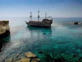 An aerial view of a majestic pirate ship cruising through crystal-clear waters, showcasing the stunning coastline and vibrant marine life — perfect for adventure seekers.