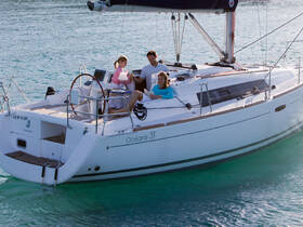 A group enjoys a relaxing moment aboard an Océanis 31 sailboat, showcasing the joy of sailing in beautiful waters.