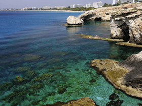 A stunning view of a clear turquoise coastline with rocky formations, perfect for showcasing the natural beauty of the area and ideal for boat trips or beach outings.