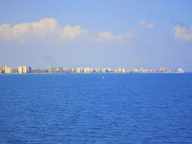 A distant view of a coastal city skyline over blue waters, but the image lacks clarity and detail.