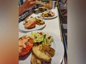 Delicious grilled lobster served with seasoned potatoes and fresh salad, perfect for a gourmet experience on board.