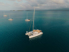 Aerial view of a beautiful catamaran sailing in tranquil waters, surrounded by other vessels — perfect for exploring coastal destinations.