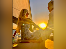 A couple enjoys a romantic sunset sail, capturing a perfect moment of connection against the backdrop of a stunning sunset.