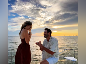 A romantic sunset proposal on a boat, capturing a couple's joyful moment as they celebrate their love against a stunning backdrop.
