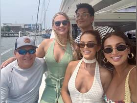 A cheerful group of friends poses for a photo on a yacht, capturing the essence of summer fun and celebration on the water.