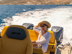 A woman enjoys a sunny day on the water, smiling while seated in a boat, capturing the essence of a perfect boating experience.