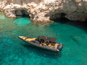 An aerial view of a sleek speedboat navigating through crystal-clear turquoise waters, perfect for exploring coastal caves and enjoying the sun.