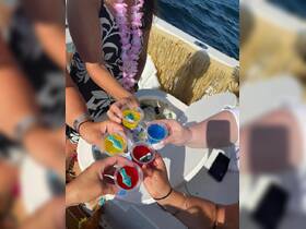 A group of friends cheers with colorful cocktails on a boat, celebrating a fun day on the water — perfect for party vibes and memorable moments.