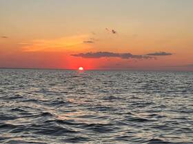 A stunning sunset over the ocean, capturing the vibrant colors of the sky as the sun dips below the horizon — perfect for tranquil evening boat cruises.