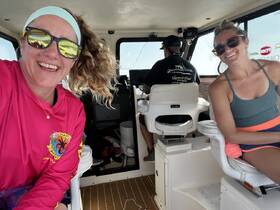 Two friends enjoy a moment inside the boat's cabin, showcasing the comfortable seating and helm area — perfect for a day out on the water.