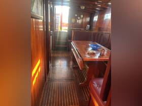 Interior view of a cozy boat cabin featuring wooden finishes, a dining table, and seating area, perfect for relaxing during a nautical adventure.