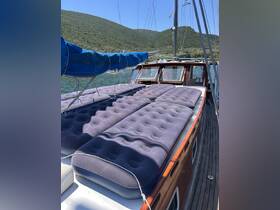 Inflatable lounge pads are arranged on the deck of a sailboat, providing a comfortable space for relaxation while enjoying the scenic views of the surrounding hills.