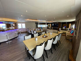 Interior view of a spacious dining area on a boat, featuring elegant seating and a well-equipped bar, perfect for gatherings and meals at sea.