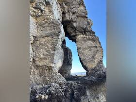 An abstract view of rock formations against a clear blue sky, creating a unique natural archway.