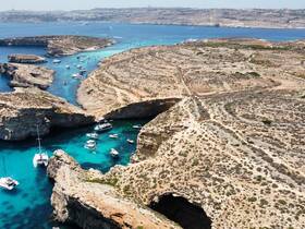 A stunning aerial view of a picturesque coastline with multiple boats anchored in crystal-clear waters, showcasing the natural beauty of the islands.