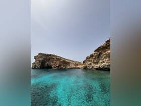 A stunning view of rocky cliffs meeting crystal-clear turquoise waters, showcasing the natural beauty of the coastline — perfect for island exploration and scenic boat trips.