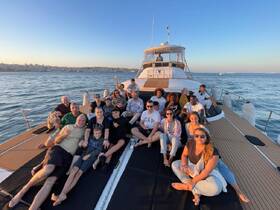 A lively group enjoys a sunset celebration aboard a yacht, sharing drinks and laughter, creating unforgettable memories on the water.