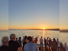 A vibrant group enjoys a sunset celebration on the water, creating unforgettable memories against a stunning backdrop.
