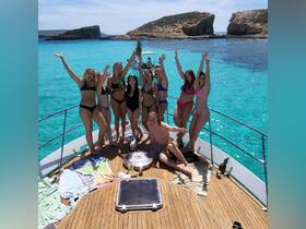 A lively group of friends celebrates on the deck of a yacht, enjoying the sun and turquoise waters — perfect for summer parties and memorable outings.